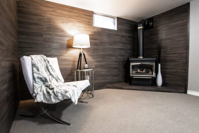 warm-basement-with-fireplace warm basement with chair, blanket, and fireplace