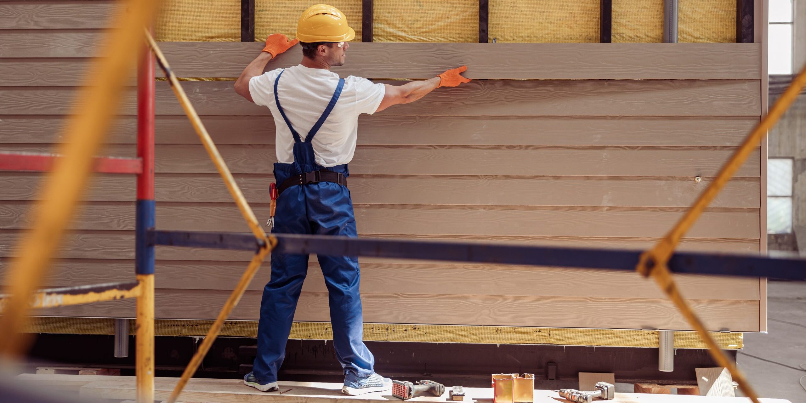 Male worker building cabin at construction site Siding Contractor Fort Collins CO