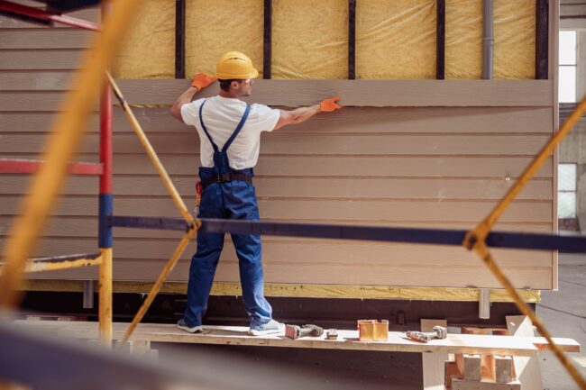 Male worker building cabin at construction site Siding Contractor Fort Collins CO