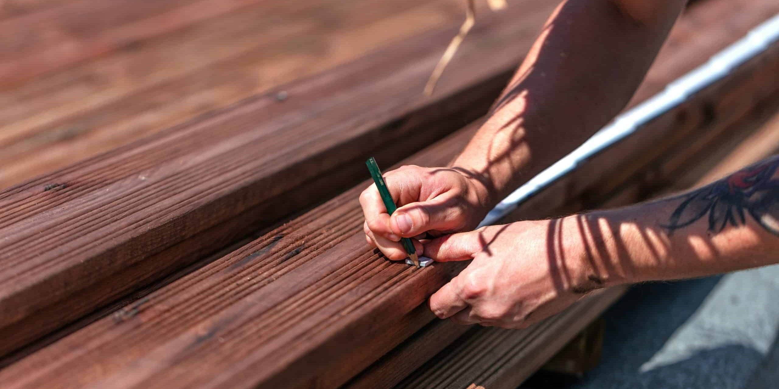 Handyman installing wooden flooring in patio, working with drilling machine. Deck Builders Fort Collins CO